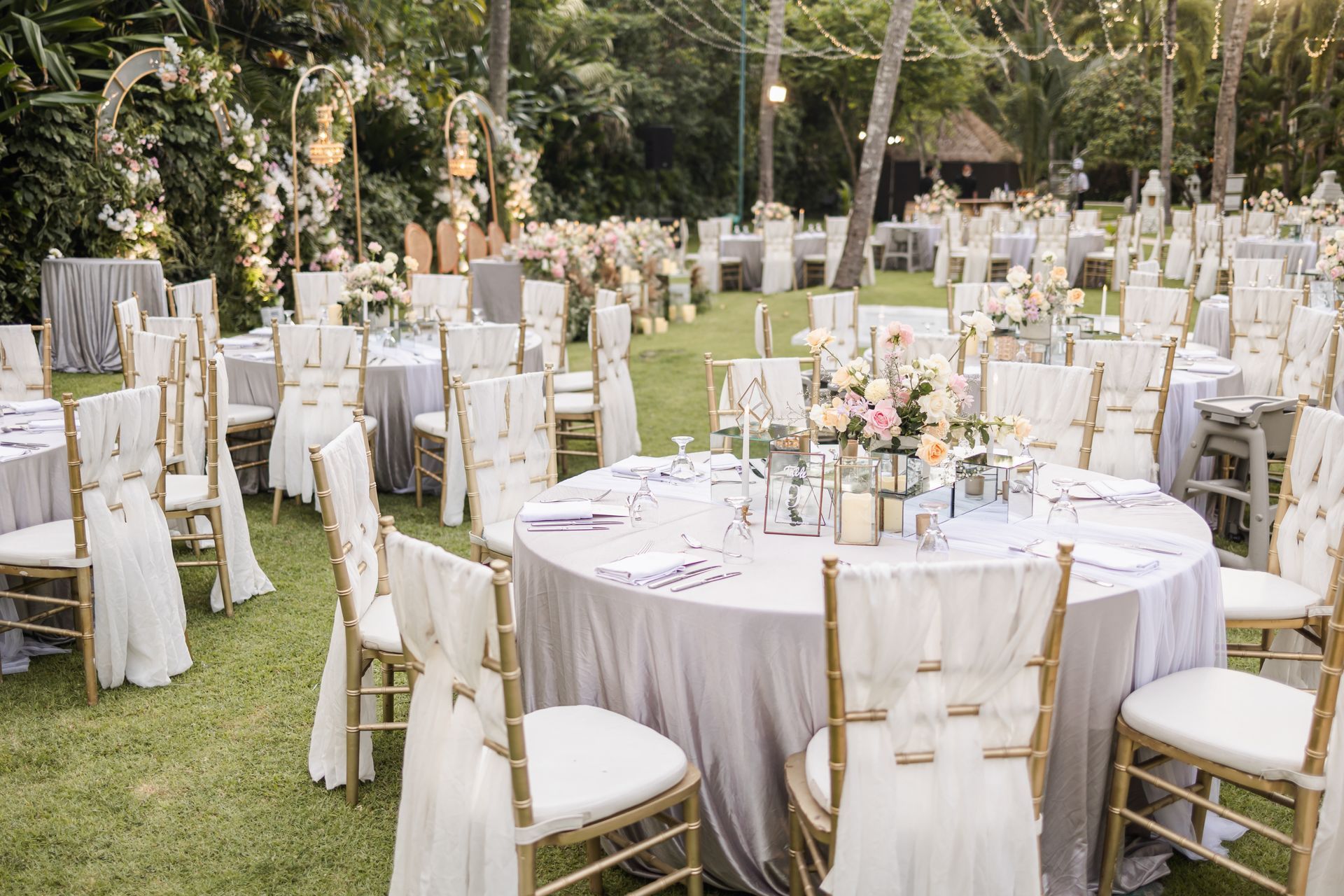 Réception de mariage en plein air avec tables dressées, chaises et centres de table floraux.