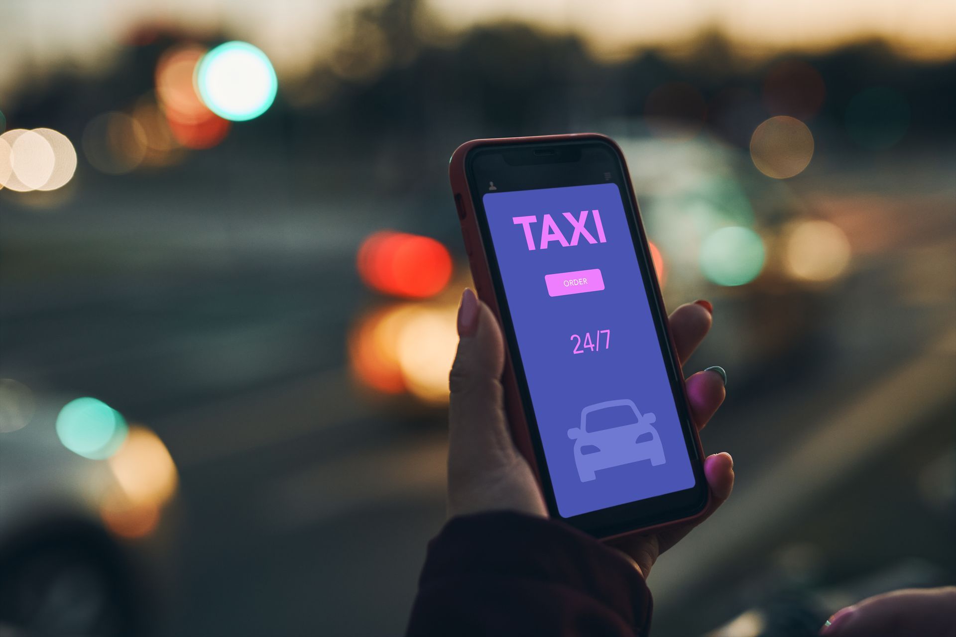 Personne tenant un téléphone affichant l'interface d'une application de taxi à l'extérieur, de nuit.