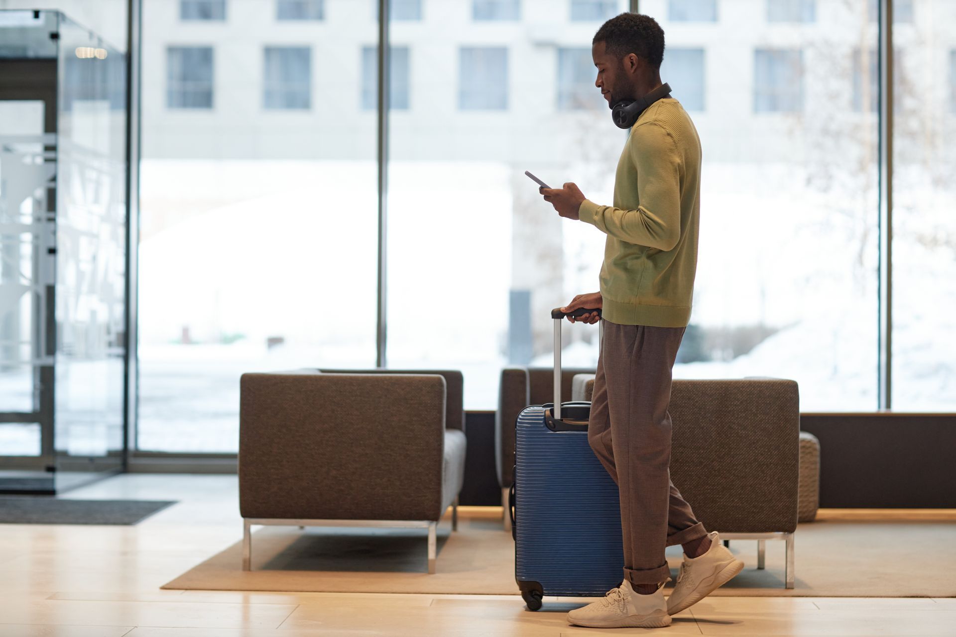 Un homme marche dans le hall d'une gare, faisant rouler une valise.
