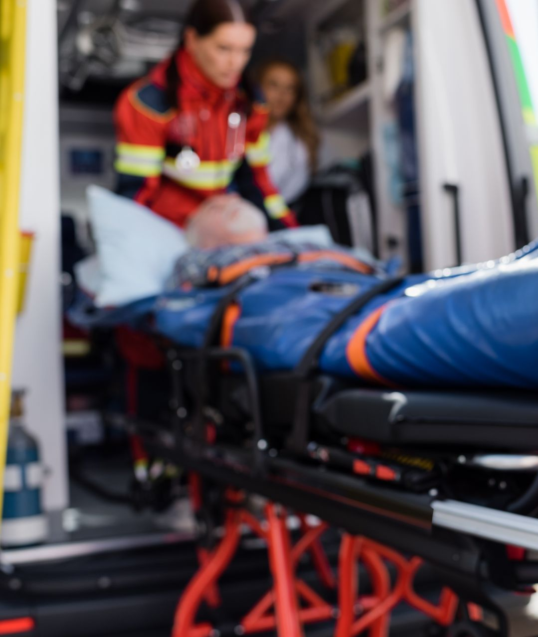 Des ambulanciers avec un patient sur une civière à l'intérieur d'une ambulance.