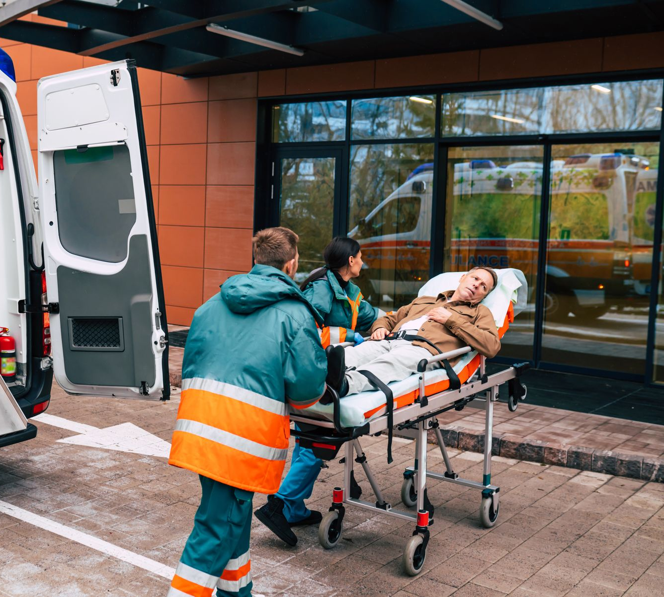 Des ambulanciers transportent un patient sur une civière vers l'entrée d'un hôpital.