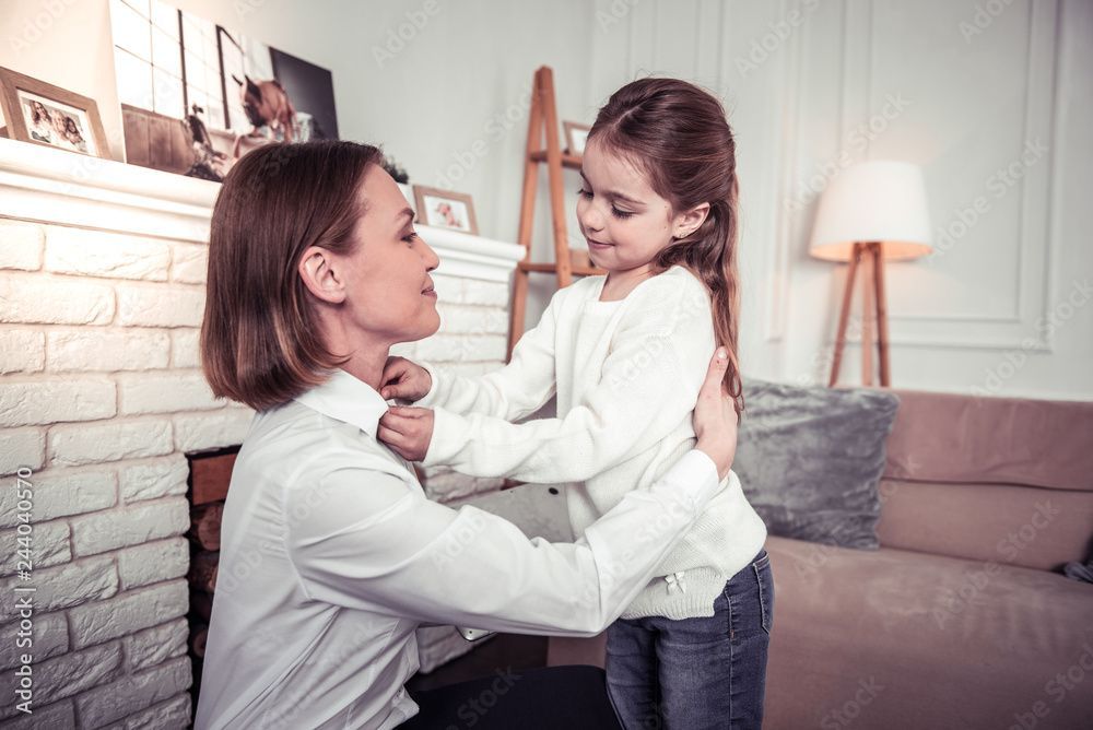 Une femme tient une petite fille dans ses bras dans un salon.