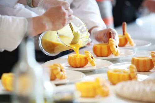Un groupe de personnes prépare de la nourriture dans une cuisine.