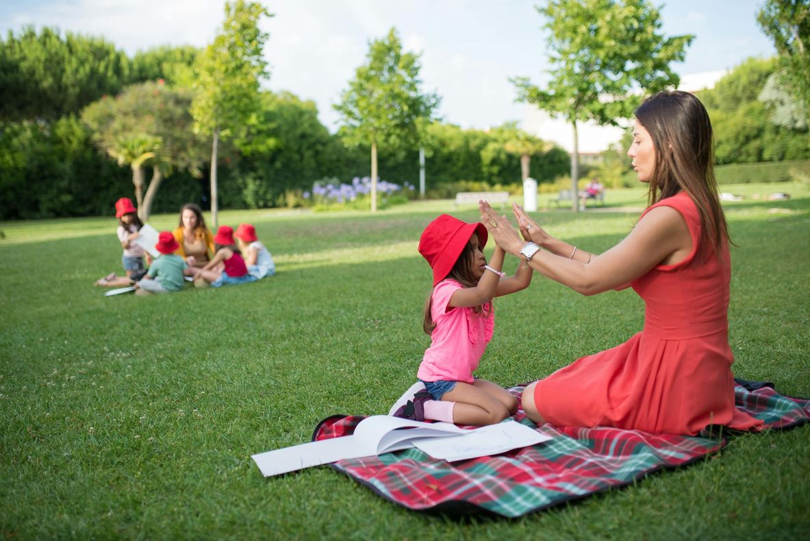 Une femme et une petite fille sont assises sur une couverture dans un parc.