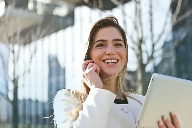 Una mujer sostiene una tableta y habla por un teléfono celular.