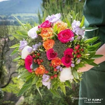 Bouquet lumineux de fleurs mêlant des fleurs roses, orange, blanches et lavande, tenu en extérieur