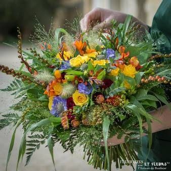 Bouquet de fleurs colorées aux tons vifs, composé de fleurs jaunes, orange, violettes et rouges, agrémentées de feuillage