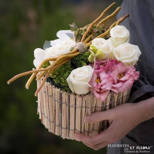 Bouquet rond de roses blanches et roses, avec des branches rustiques et du feuillage