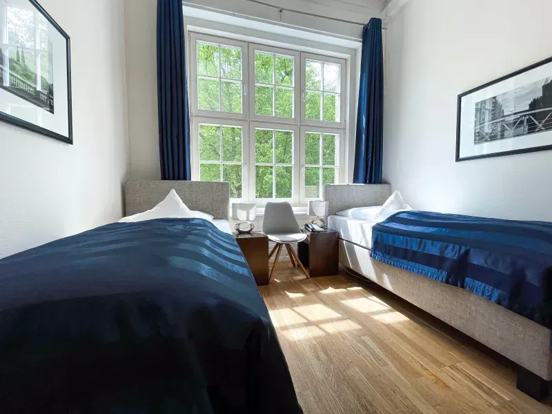 Ein Schlafzimmer mit zwei Betten, einem Stuhl und einem Fenster.