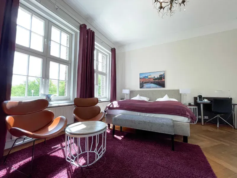 Ein Schlafzimmer mit einem Kingsize-Bett, Stühlen, einem Tisch und einer Bank.