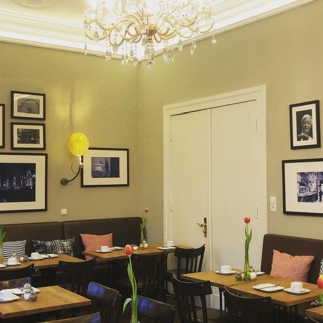Interieur eines gemütlichen Restaurants mit Holztischen, dunklen Stühlen, sanfter Wandbeleuchtung