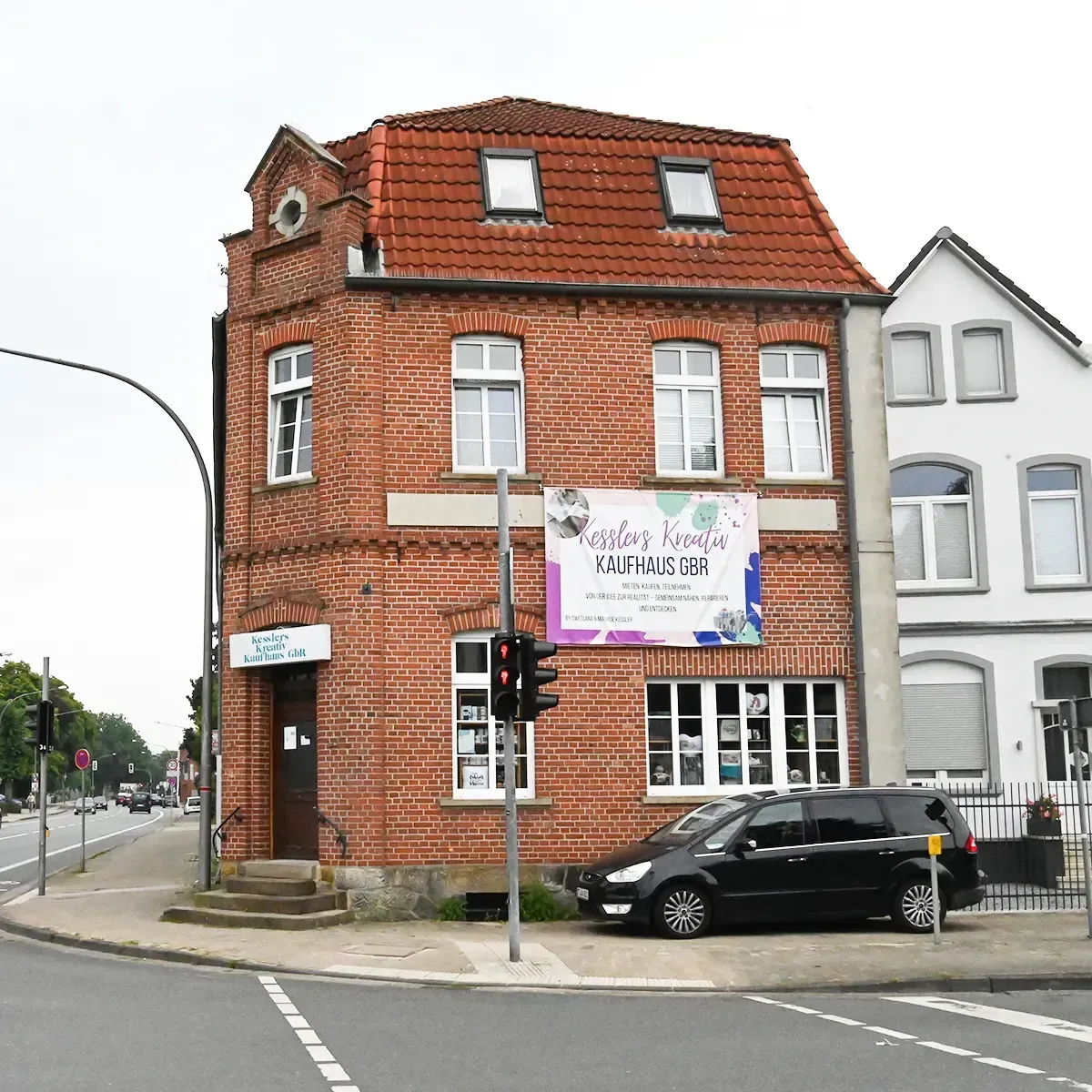 Rotes Backsteingebäude an einer Straßenecke, davor parkt ein Auto. Am Gebäude ist ein Banner in koreanischer Sprache angebracht.