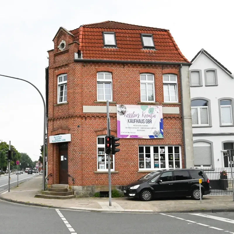Rotes Backsteingebäude an einer Straßenecke, davor parkt ein Auto. Am Gebäude ist ein Banner in koreanischer Sprache angebracht.