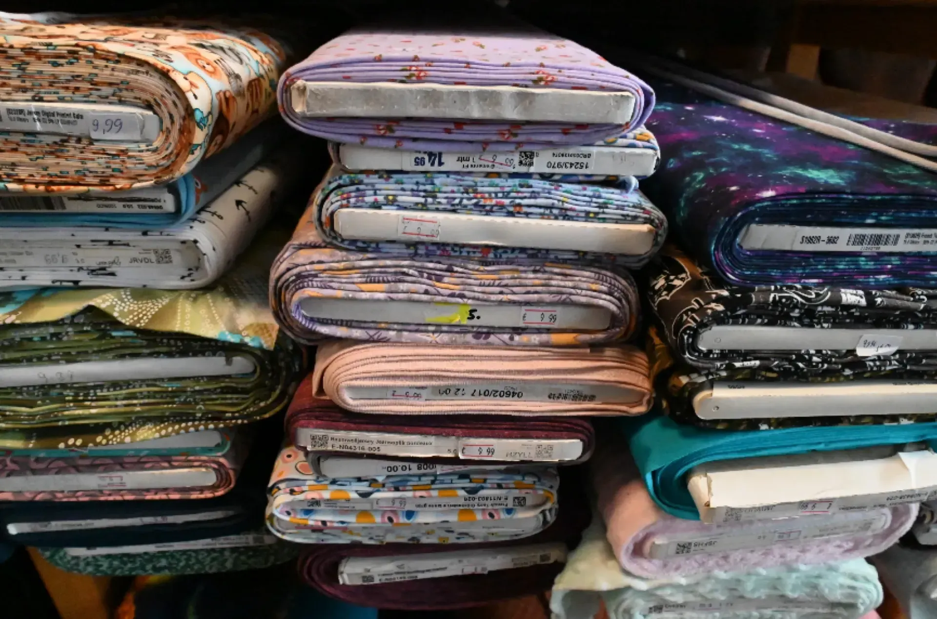 Regale voller Rollen bunter Stoffe mit verschiedenen Mustern und Texturen.