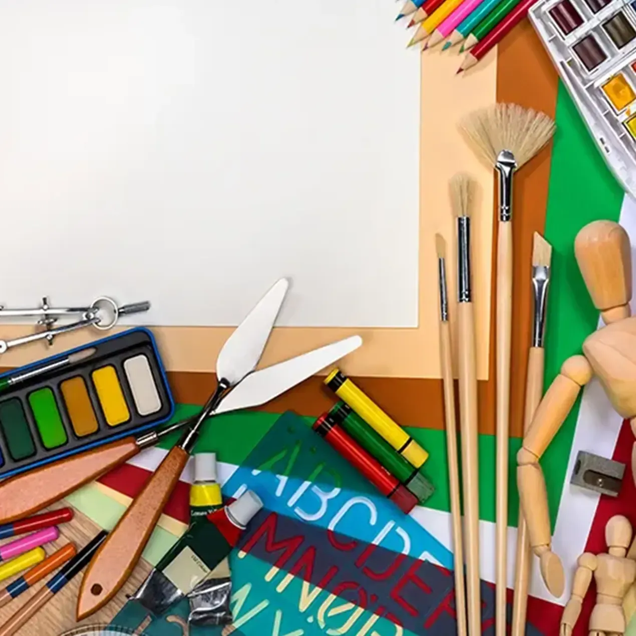Künstlerbedarf, darunter Pinsel, Farben, Bleistifte, Palettenmesser und Holzfiguren, umgeben leeres Papier.
