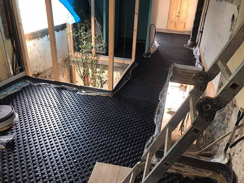 Pasarela metálica negra con escalera en un estrecho patio interior o hueco de escalera.