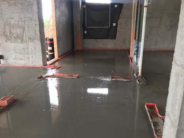 Zona de construcción interior inundada con agua estancada y paredes de hormigón y desagües del suelo al descubierto.