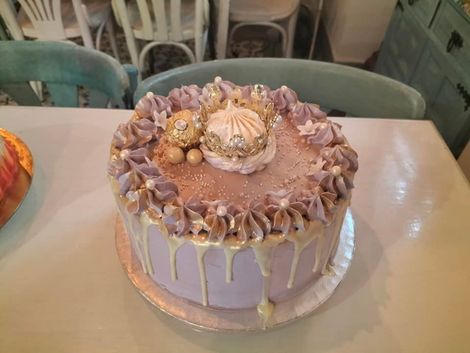 Un pastel morado con glaseado dorado está sobre una mesa.