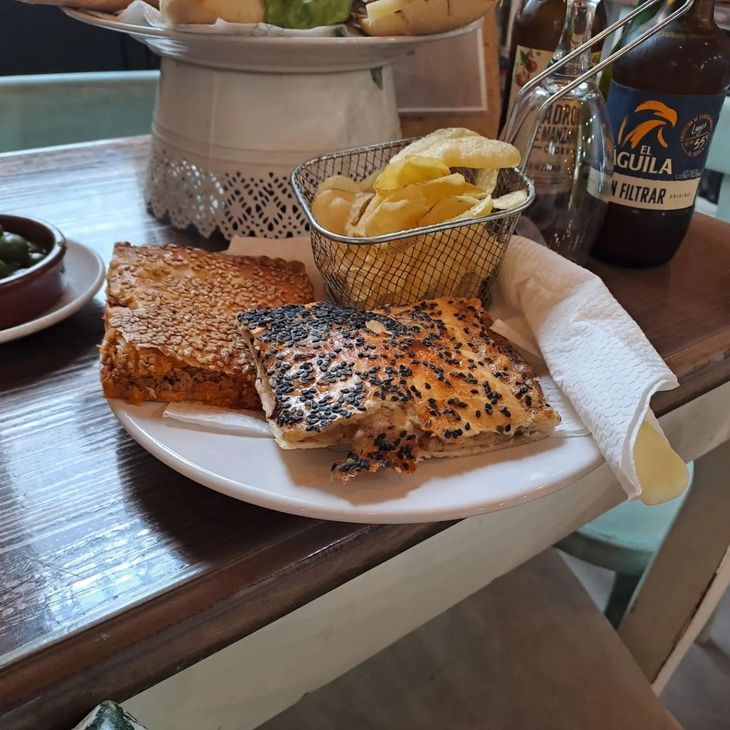 Una botella de guila reposa sobre una mesa junto a un plato de comida.