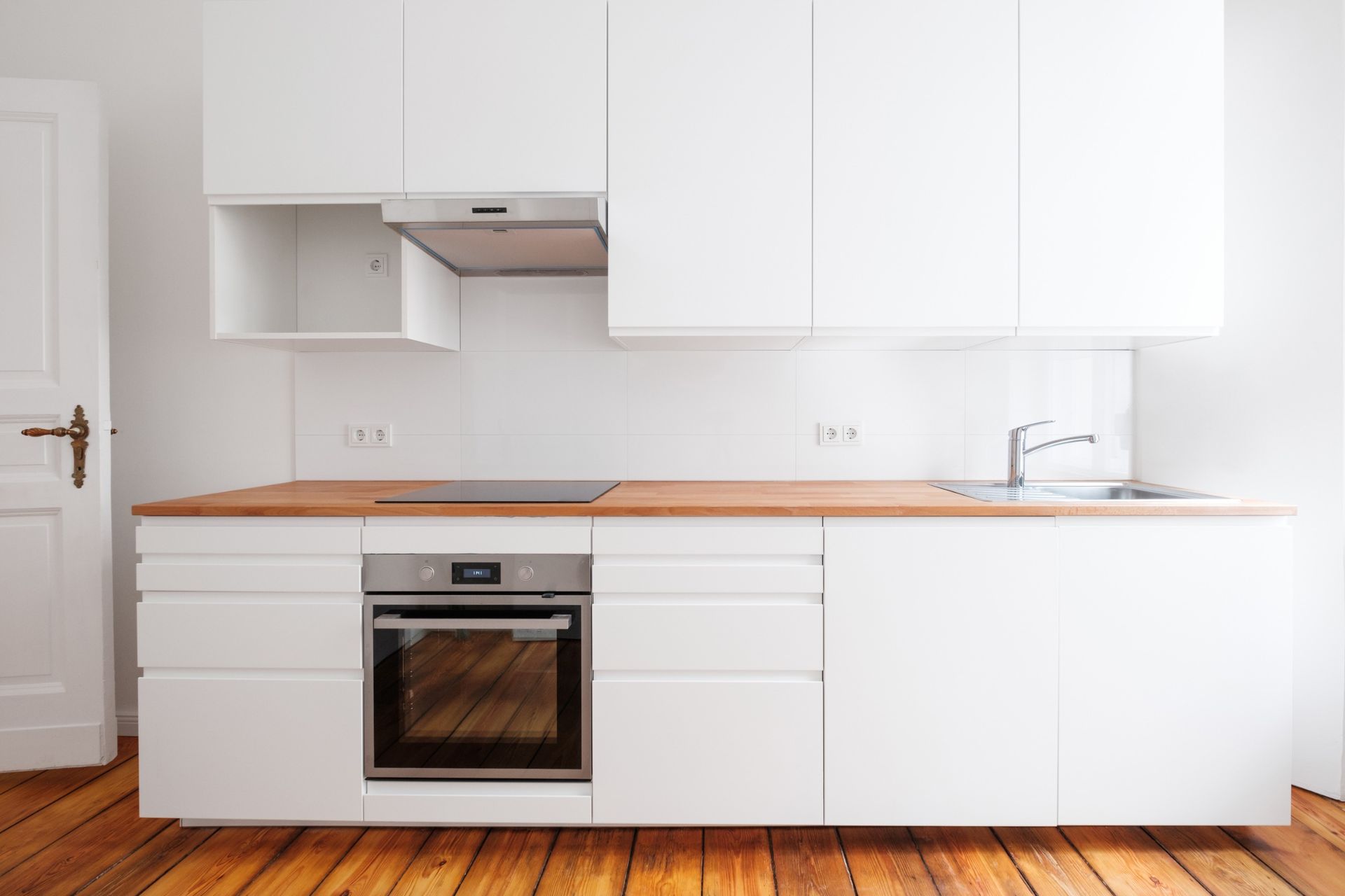 Una cocina con gabinetes blancos y una encimera de madera.