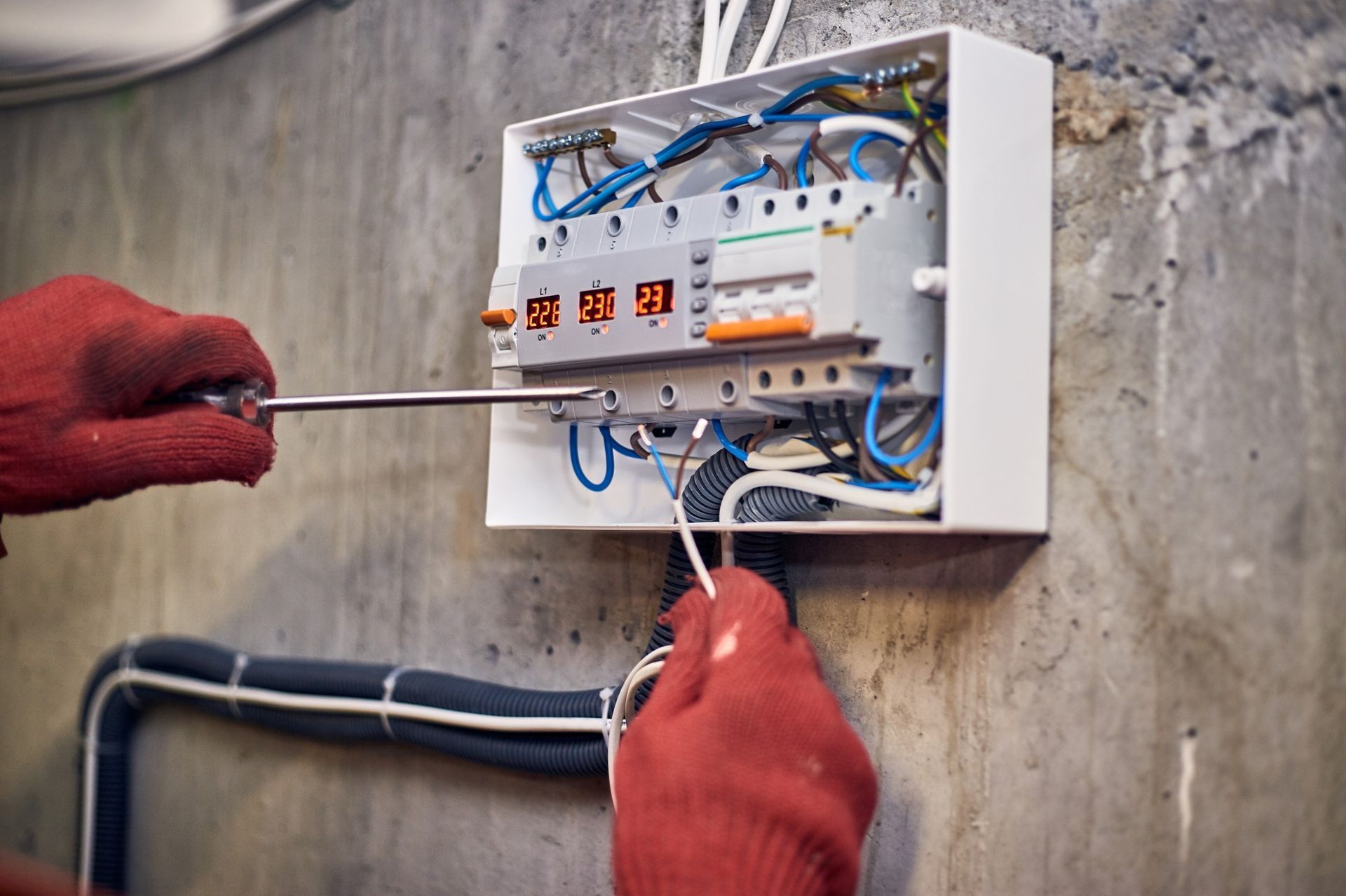 Una persona está trabajando en una caja eléctrica con un destornillador.