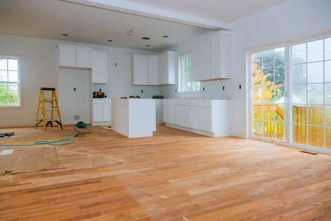 Una cocina en construcción con pisos de madera y gabinetes blancos.