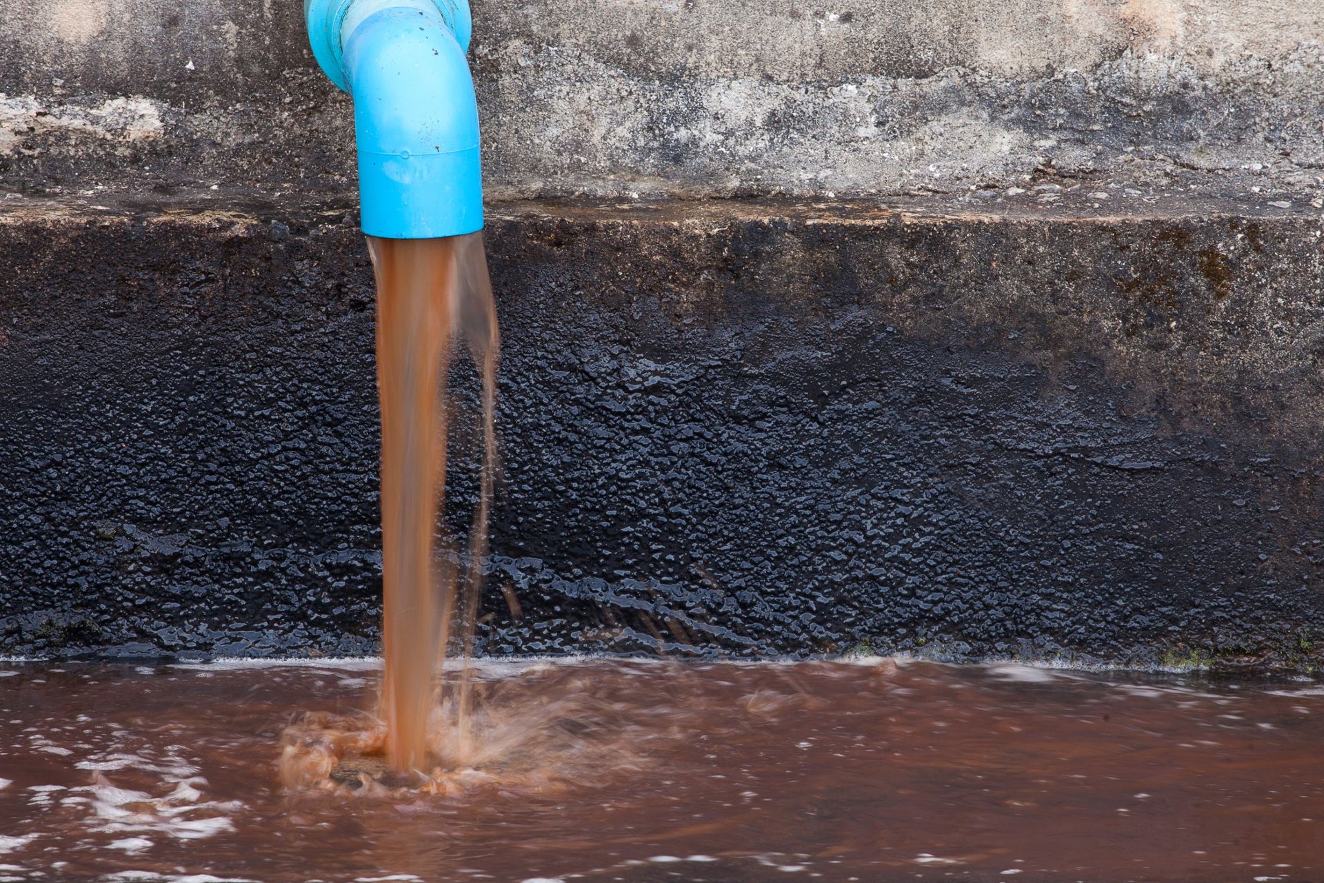 Sale agua marrón de una tubería azulror