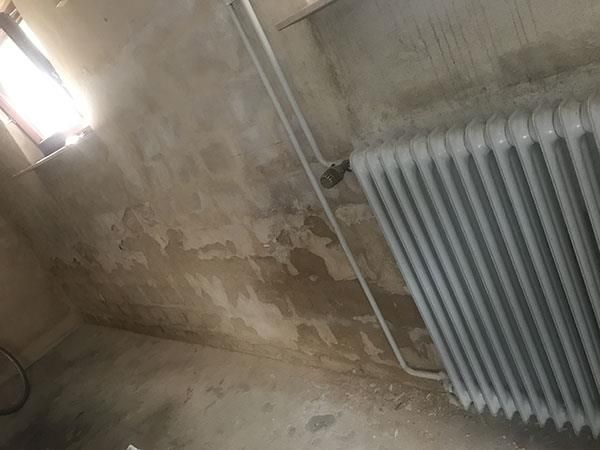 Ein weißer Heizkörper steht in einem Raum neben einem Fenster.