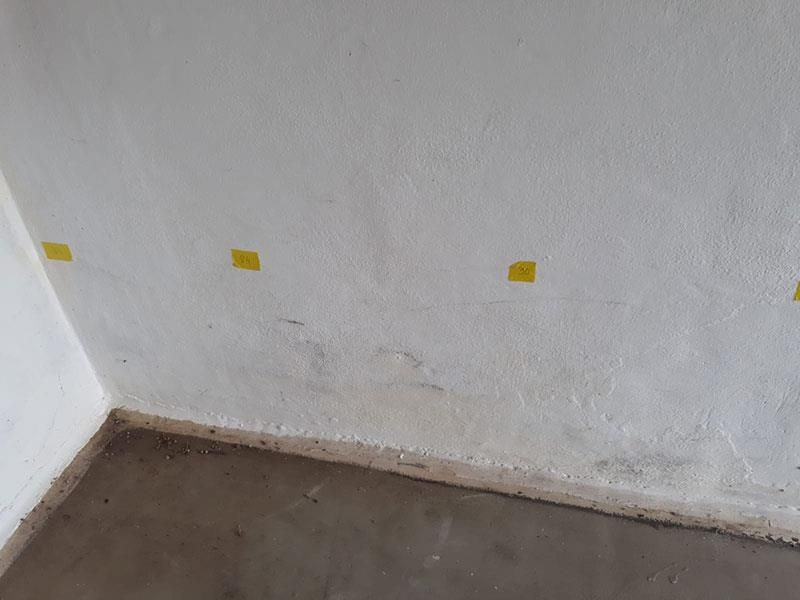 Eine Raumecke mit weißer Wand und Betonboden.