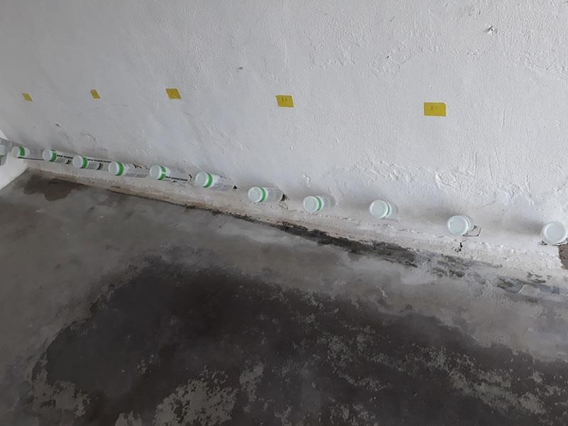 Eine Reihe Plastikbecher steht auf dem Boden neben einer Wand.