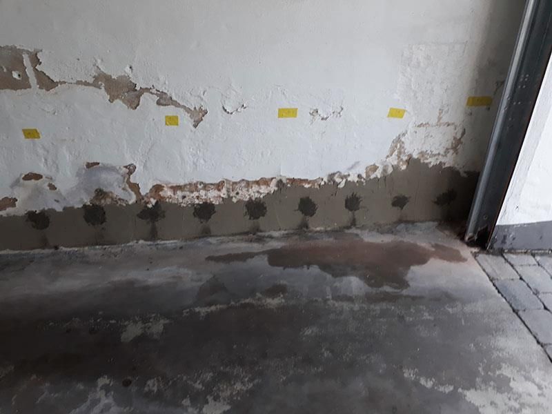 Ein Raum mit Betonboden und einer Wand mit abblätternder Farbe.