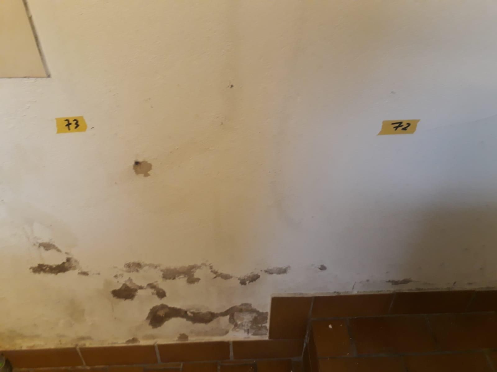 Eine weiße Wand mit zwei gelben Klebestreifen darauf.