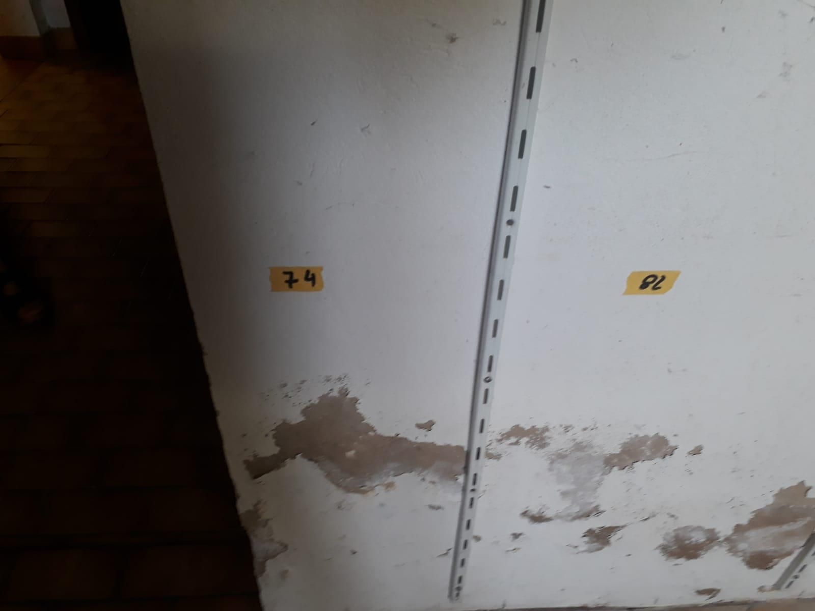 Eine weiße Wand mit zwei gelben Aufklebern darauf, auf denen 74 und 82 stehen