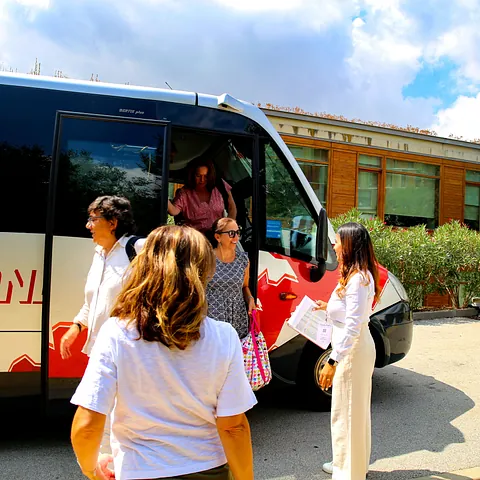 Un grupo de personas están paradas frente a un autobús con la letra L en él.