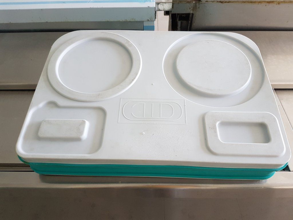 Bandeja de cafetería de color blanco y verde azulado con dos zonas de platos circulares y dos zonas rectangulares.