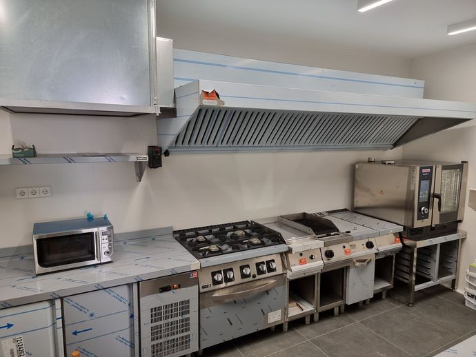 Interior del restaurante: área de bar con encimeras de granito, cocina con electrodomésticos de acero inoxidable.