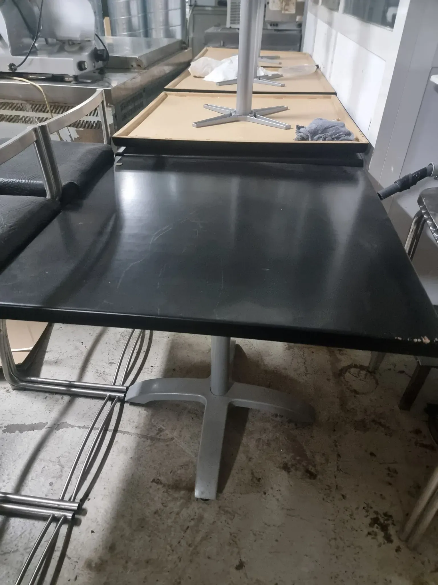 Mesa negra con base plateada en un entorno de cocina comercial.