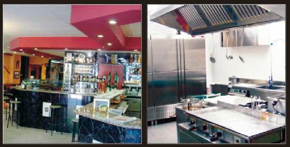 Interior del restaurante: área de bar con encimeras de granito, cocina con electrodomésticos de acero inoxidable.