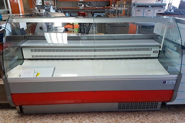 Vitrina refrigerada comercial vacía con vidrio curvo y detalles en rojo.