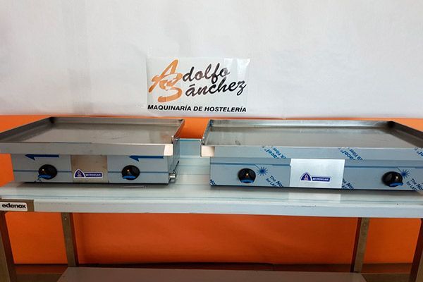 Dos planchas de acero inoxidable sobre un estante, debajo de un logotipo.