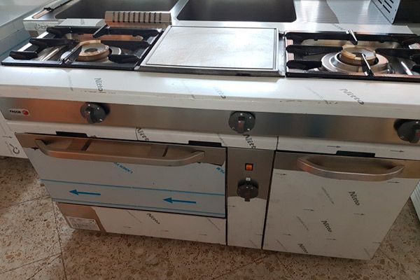 Gama de cocinas comerciales de acero inoxidable con quemadores y hornos a gas.