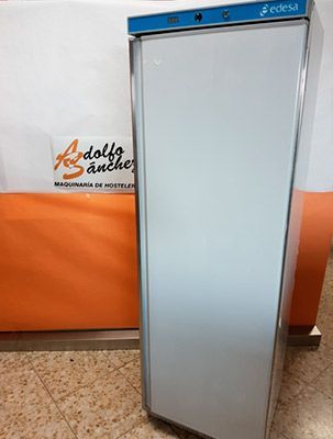 Frigorífico Edessa de color blanco en entorno comercial, con paredes en color naranja y blanco.