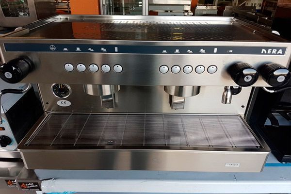 Cafetera espresso de acero inoxidable con múltiples botones y lanzas de vapor.