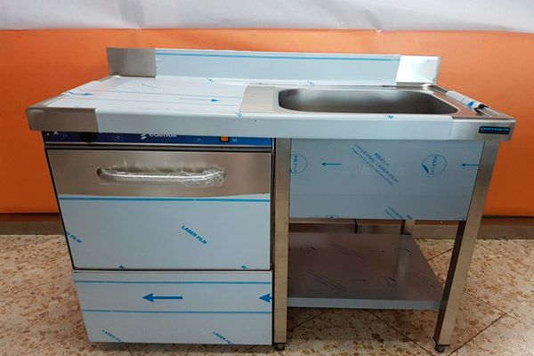 Lavavajillas comercial y fregadero en acero inoxidable sobre soporte.