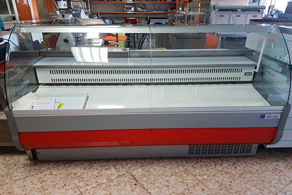 Vitrina refrigerada vacía con exterior rojo y gris, dentro de una tienda.