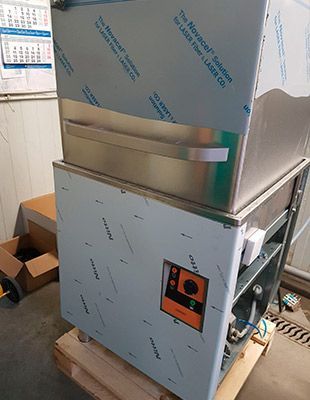 Lavadora de piezas industrial en acero inoxidable sobre palet, con panel de control.