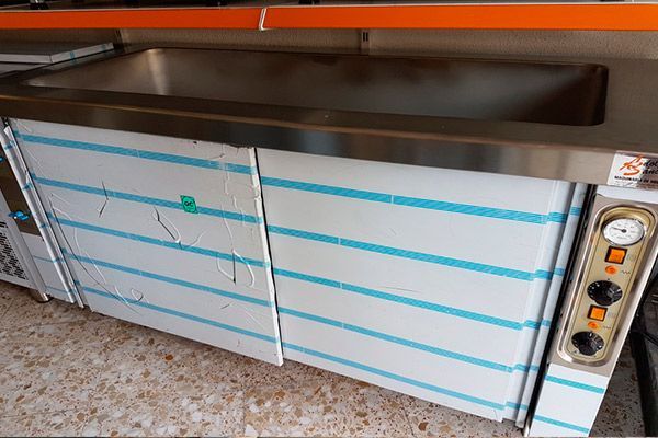 Calentador de alimentos comercial de acero inoxidable con controles y película protectora azul.