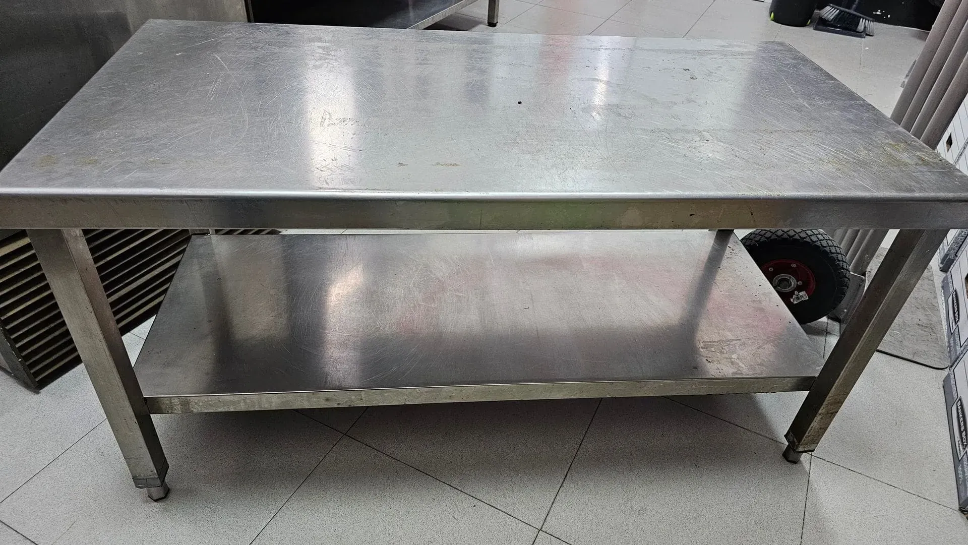 Mesa de trabajo de acero inoxidable con estante inferior en un taller.