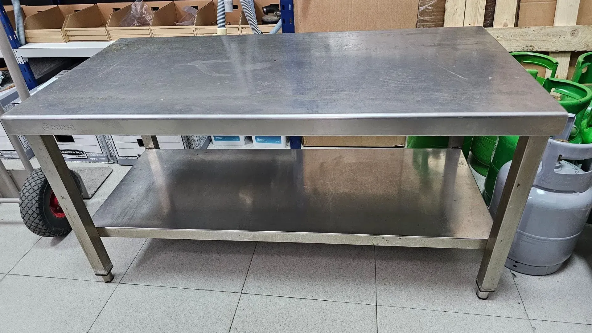 Mesa de trabajo en acero inoxidable con estante inferior, en zona de almacenaje.