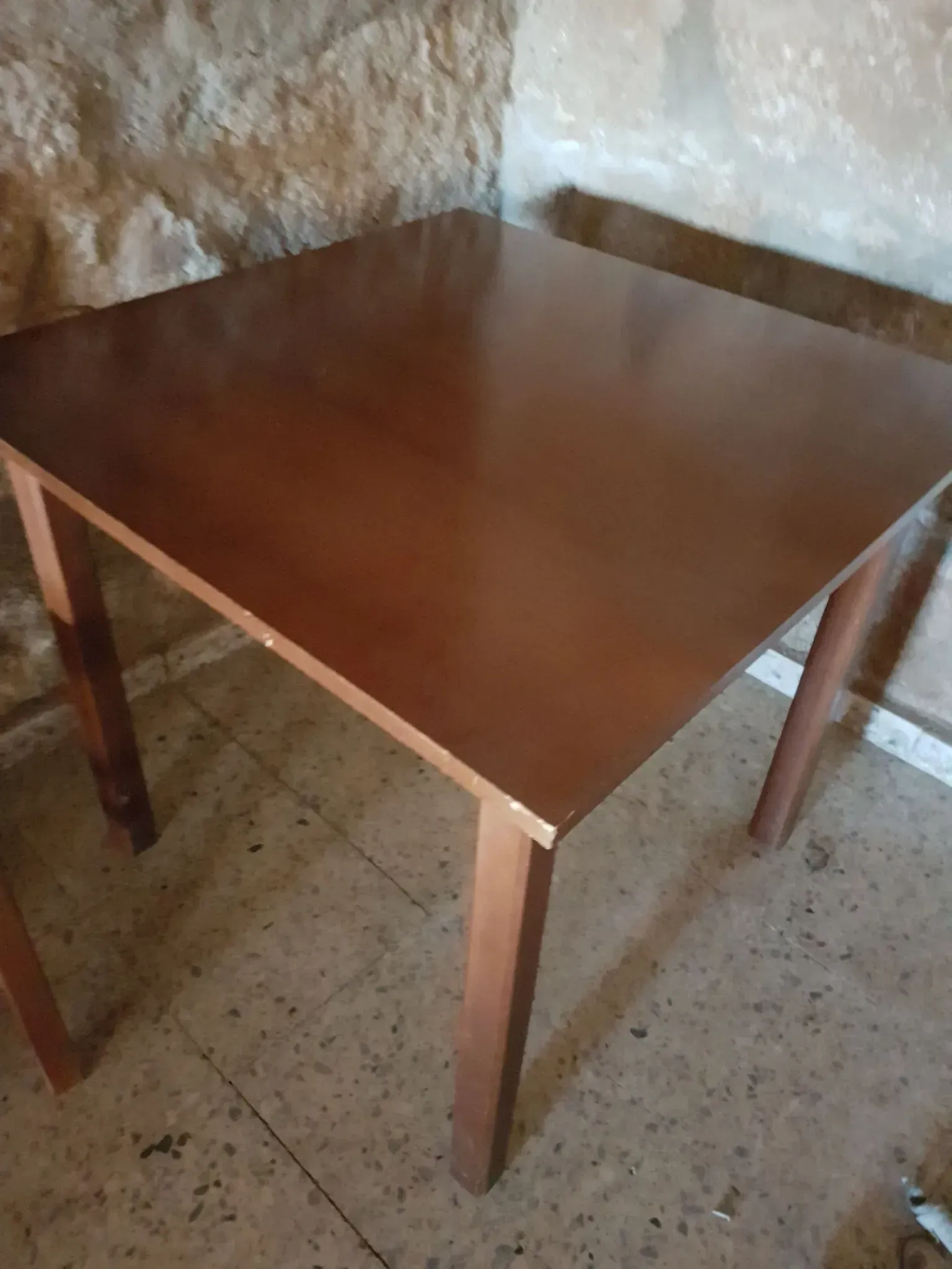 Mesa cuadrada de madera marrón con cuatro patas.